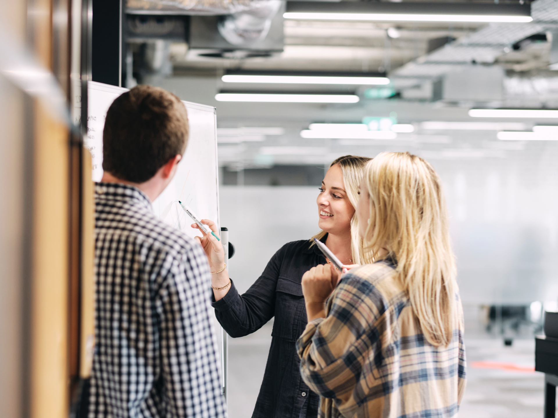 A team collaborating while drawing on a whiteboard